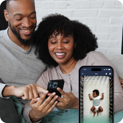 couple looking at nanit app on mobile while child is sleeping with mobile displayed